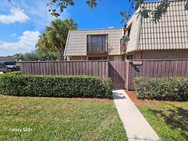 5152 51st Way, West Palm Beach, FL 33409 - view of home's exterior featuring mansard roof, a gate, a tile roof, brick siding, and a balcony