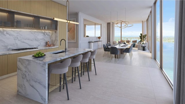 550 S Australian Ave Unit 2206, West Palm Beach, FL 33401 - kitchen featuring modern cabinets, tasteful backsplash, an island with sink, a wall of windows, and gas cooktop