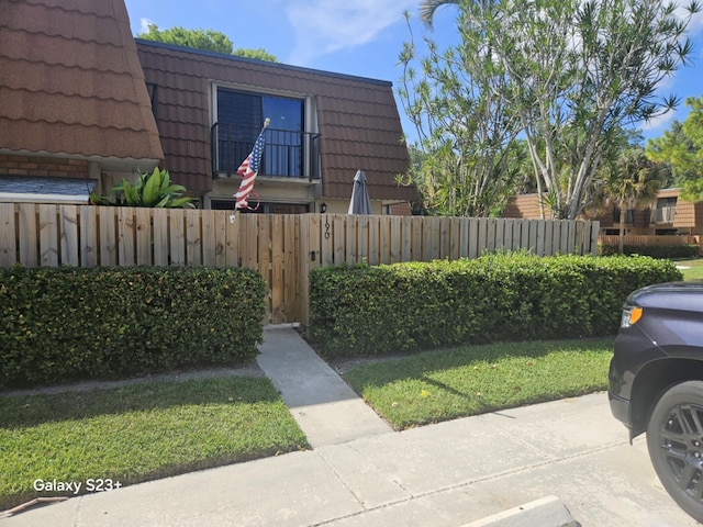 190 Charter Way, West Palm Beach, FL 33407 - view of side of home with a fenced front yard, a tiled roof, and mansard roof