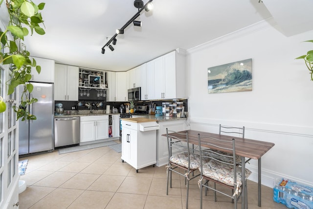 2140 White Pine Cir Unit A, Greenacres, FL 33415 - kitchen featuring appliances with stainless steel finishes, white cabinetry, light tile patterned floors, backsplash, and crown molding