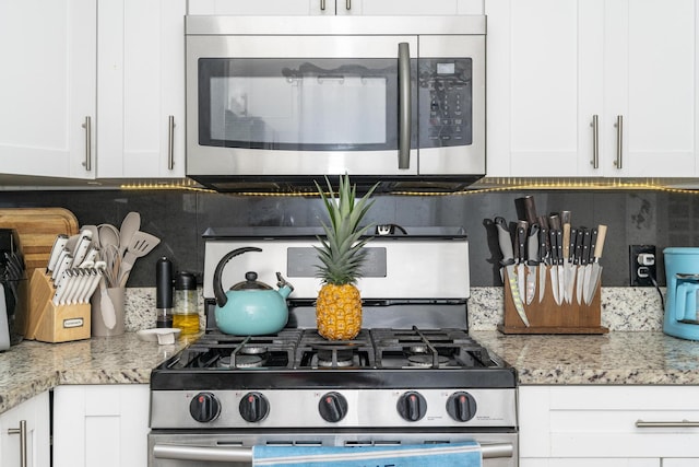 2140 White Pine Cir Unit A, Greenacres, FL 33415 - kitchen featuring stainless steel microwave, gas stove, tasteful backsplash, and white cabinets