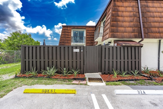 2140 White Pine Cir Unit A, Greenacres, FL 33415 - view of side of property featuring a fenced front yard, mansard roof, and uncovered parking