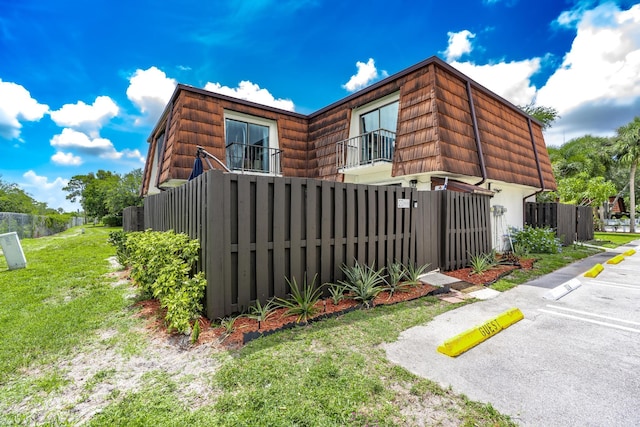 2140 White Pine Cir Unit A, Greenacres, FL 33415 - view of side of home featuring a balcony, mansard roof, and uncovered parking