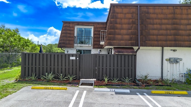 2140 White Pine Cir Unit A, Greenacres, FL 33415 - view of side of property featuring mansard roof, a fenced front yard, uncovered parking, and stucco siding