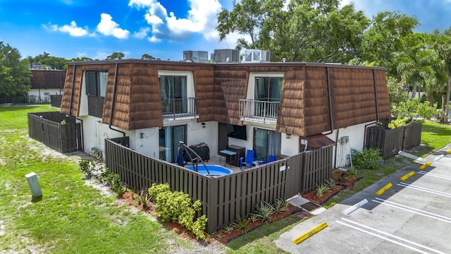 2140 White Pine Cir Unit A, Greenacres, FL 33415 - rear view of house with a balcony, mansard roof, uncovered parking, and stucco siding