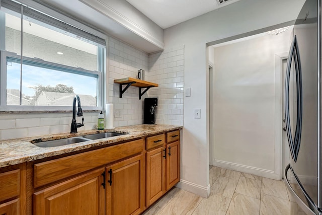 5914 SE Mitzi Ln, Stuart, FL 34997 - kitchen featuring freestanding refrigerator, brown cabinets, light stone counters, and tasteful backsplash