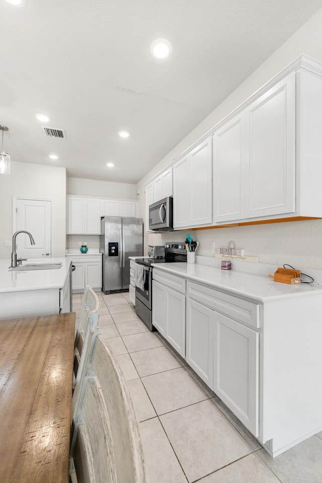 2418 Post St, Palm Springs, FL 33406 - kitchen featuring appliances with stainless steel finishes, light countertops, light tile patterned flooring, white cabinets, and recessed lighting