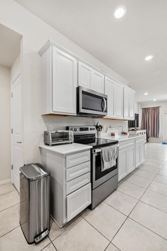 2418 Post St, Palm Springs, FL 33406 - kitchen with stainless steel appliances, light tile patterned floors, recessed lighting, white cabinetry, and light countertops