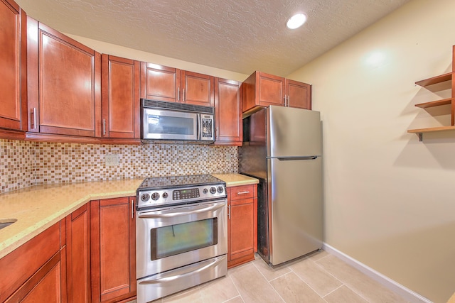 2050 Oleander Blvd Unit 5301, Fort Pierce, FL 34950 - kitchen with stainless steel appliances, decorative backsplash, light stone countertops, light tile patterned flooring, and brown cabinetry