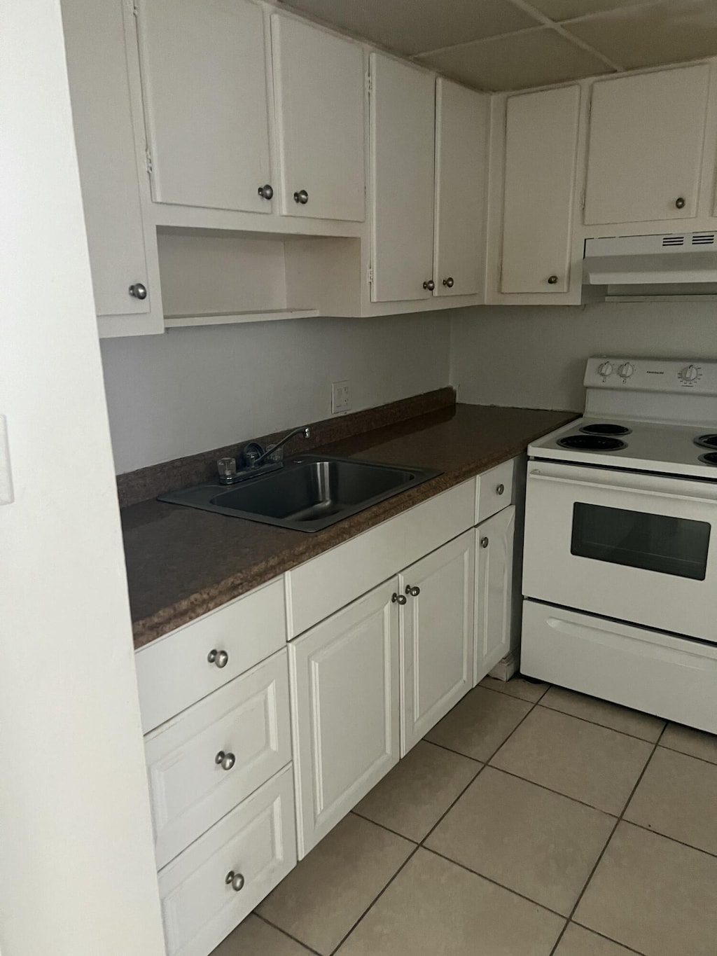 1300 NW 43rd Ter Unit 104, Lauderhill, FL 33313 - kitchen with white range with electric stovetop, exhaust hood, dark countertops, and light tile patterned floors
