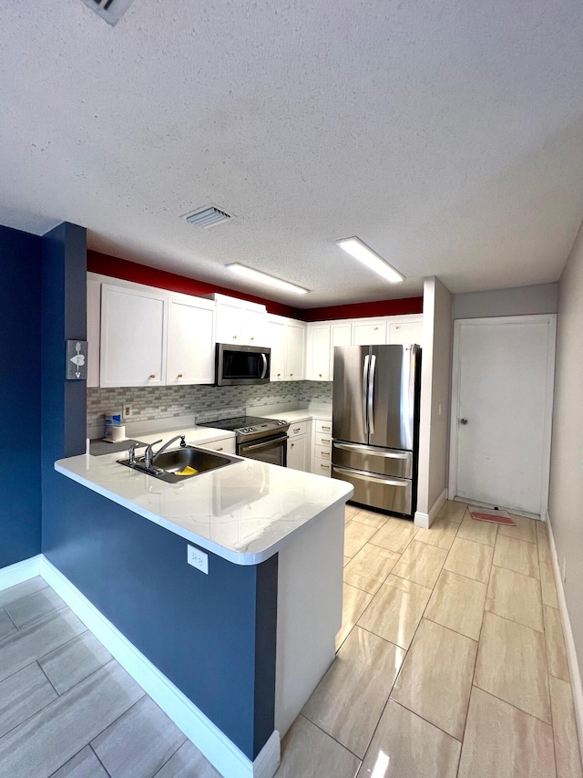 9815 Watermill Cir Unit B, Boynton Beach, FL 33437 - kitchen featuring appliances with stainless steel finishes, a peninsula, white cabinetry, backsplash, and a textured ceiling