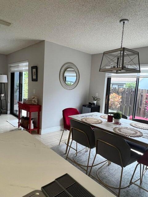 9815 Watermill Cir Unit B, Boynton Beach, FL 33437 - dining room featuring a textured ceiling and a chandelier