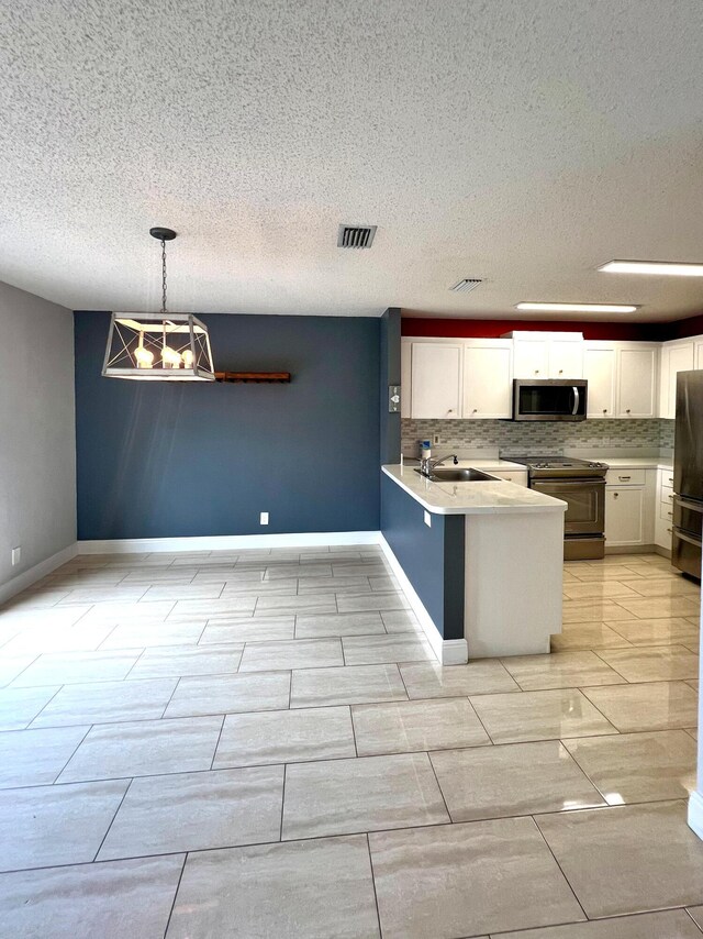 9815 Watermill Cir Unit B, Boynton Beach, FL 33437 - kitchen with appliances with stainless steel finishes, white cabinets, a peninsula, a textured ceiling, and backsplash