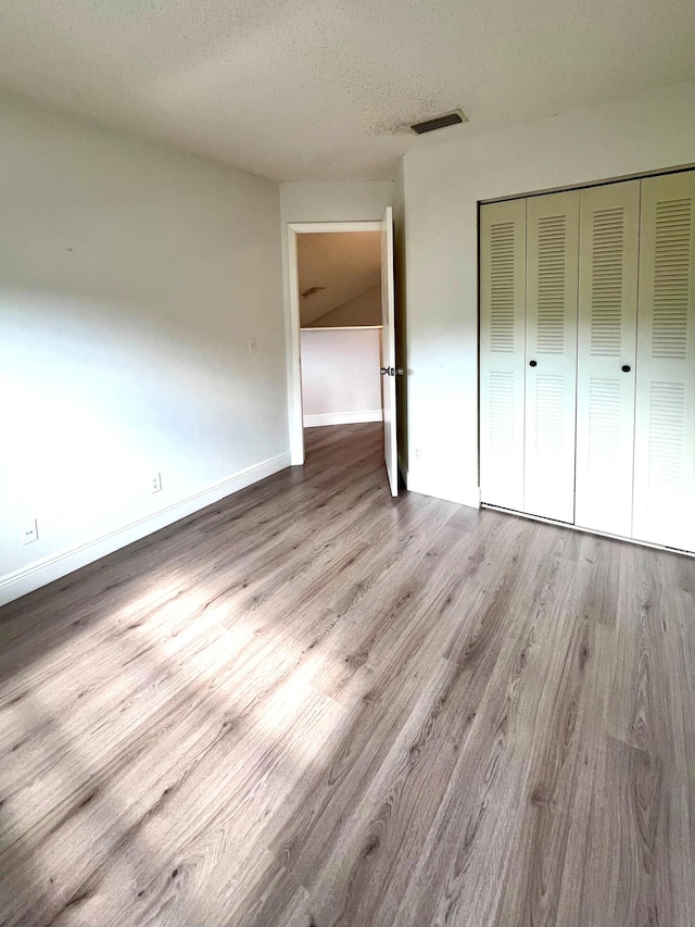 9815 Watermill Cir Unit B, Boynton Beach, FL 33437 - unfurnished bedroom featuring wood finished floors, a textured ceiling, and a closet