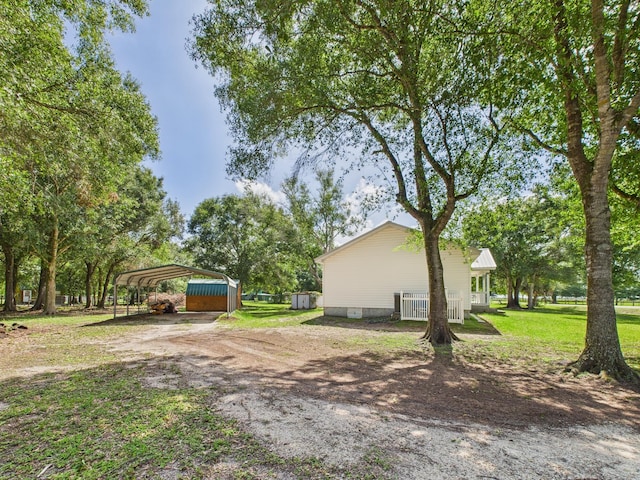 7281 NW 90th Ct, Okeechobee, FL 34972 - view of side of home featuring a detached carport, dirt driveway, a yard, and a storage unit