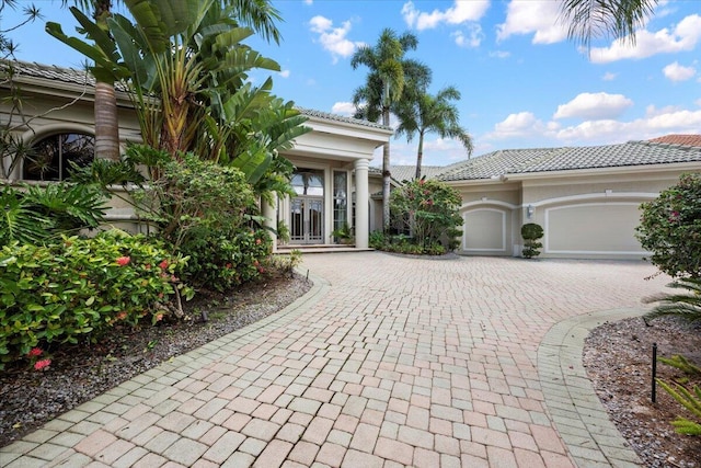8571 Egret Lakes Ln, West Palm Beach, FL 33412 - view of front of house featuring decorative driveway, a tiled roof, an attached garage, and french doors