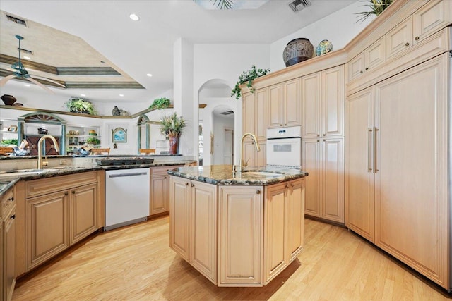 8571 Egret Lakes Ln, West Palm Beach, FL 33412 - kitchen featuring white appliances, dark stone counters, light wood-type flooring, arched walkways, and a ceiling fan