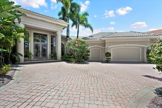 8571 Egret Lakes Ln, West Palm Beach, FL 33412 - view of front of home with french doors, an attached garage, decorative driveway, a tile roof, and stucco siding