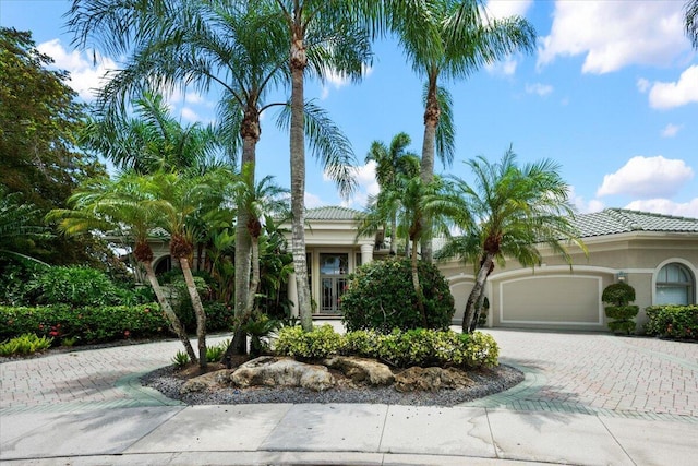 8571 Egret Lakes Ln, West Palm Beach, FL 33412 - mediterranean / spanish-style house featuring decorative driveway, stucco siding, an attached garage, and a tile roof