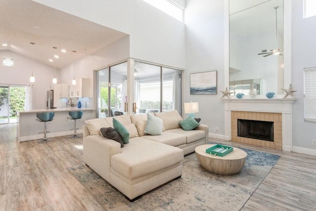 10 Hampton Ct, Palm Beach Gardens, FL 33418 - living room with high vaulted ceiling, light wood-style floors, a tiled fireplace, recessed lighting, and a ceiling fan