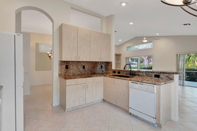 6661 Sherbrook Dr, Boynton Beach, FL 33437 - kitchen with white appliances, light brown cabinetry, a peninsula, dark stone counters, and vaulted ceiling