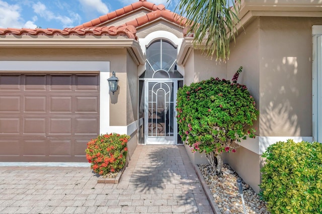6661 Sherbrook Dr, Boynton Beach, FL 33437 - view of exterior entry featuring stucco siding, a garage, and a tiled roof