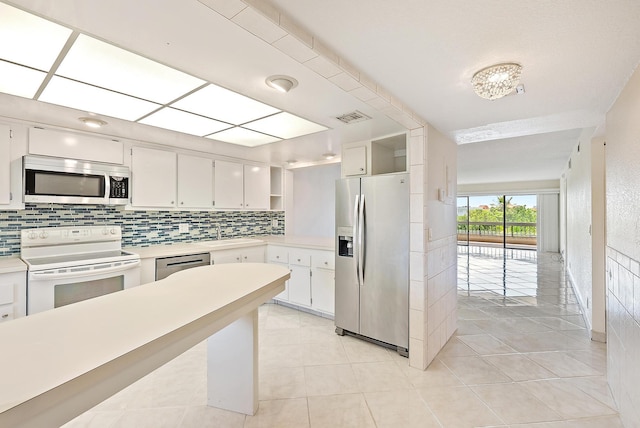 1036 US Highway 1 Unit 318, North Palm Beach, FL 33408 - kitchen featuring appliances with stainless steel finishes, tasteful backsplash, open shelves, light countertops, and white cabinetry