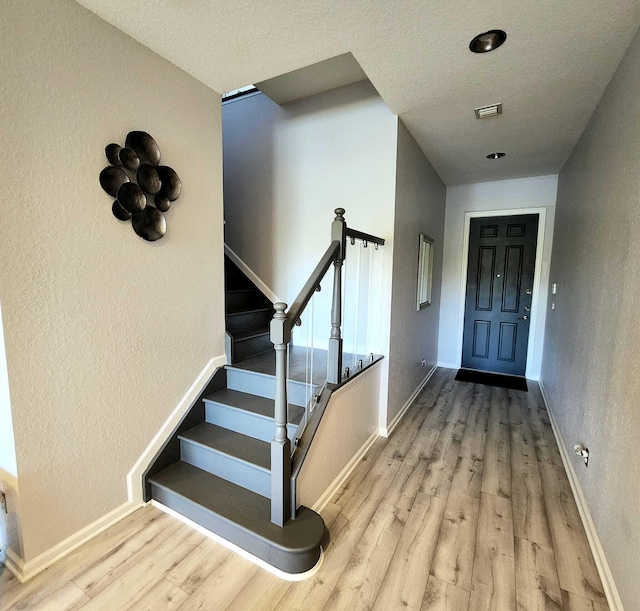 2247 SW Cape Cod Dr, Port Saint Lucie, FL 34953 - staircase with wood finished floors, a textured ceiling, and a textured wall