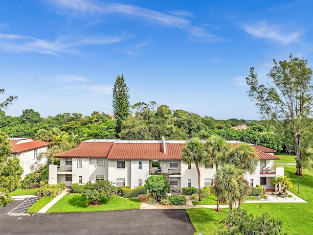 9199 Pecky Cypress Ln Unit 7H, Boca Raton, FL 33428 - view of front of home with a tiled roof, stucco siding, a front lawn, and uncovered parking