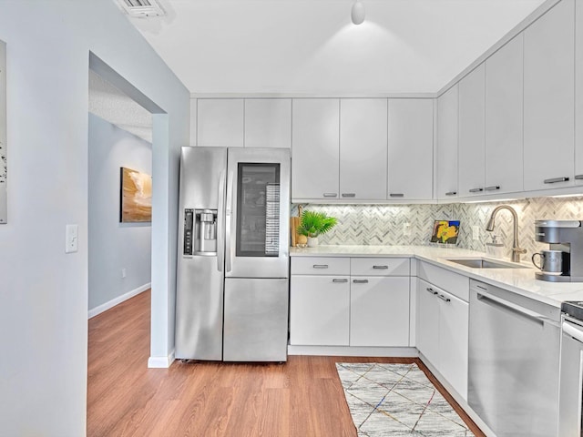 9199 Pecky Cypress Ln Unit 7H, Boca Raton, FL 33428 - kitchen with stainless steel appliances, light countertops, backsplash, and light wood-style flooring