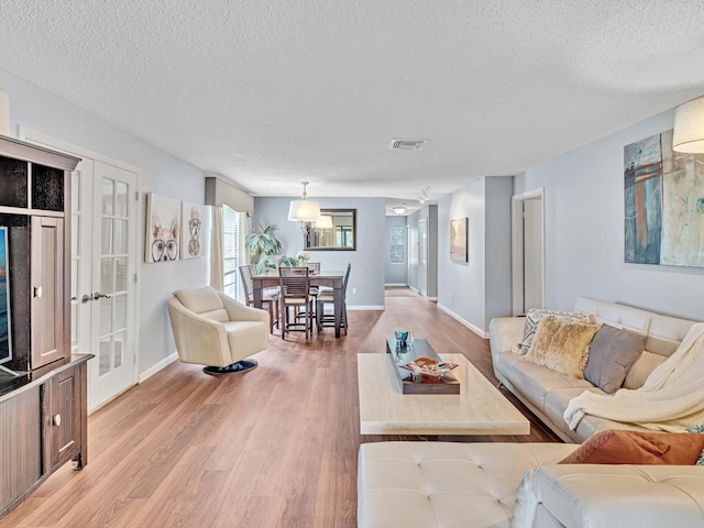 9199 Pecky Cypress Ln Unit 7H, Boca Raton, FL 33428 - living room with a textured ceiling, light wood-type flooring, and french doors