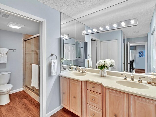 9199 Pecky Cypress Ln Unit 7H, Boca Raton, FL 33428 - bathroom featuring wood finished floors, a stall shower, double vanity, and a textured ceiling