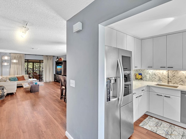 9199 Pecky Cypress Ln Unit 7H, Boca Raton, FL 33428 - kitchen featuring stainless steel refrigerator with ice dispenser, a textured ceiling, open floor plan, light wood-style floors, and decorative backsplash