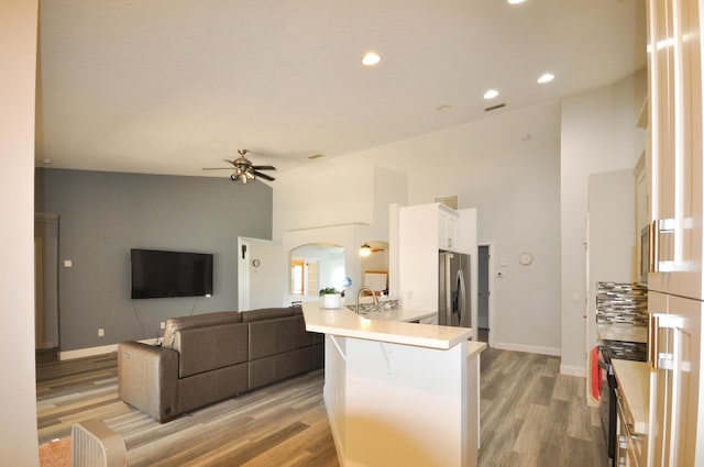 6771 NW Daffodil Ln, Port Saint Lucie, FL 34983 - kitchen with stainless steel fridge with ice dispenser, a peninsula, a ceiling fan, light wood finished floors, and recessed lighting