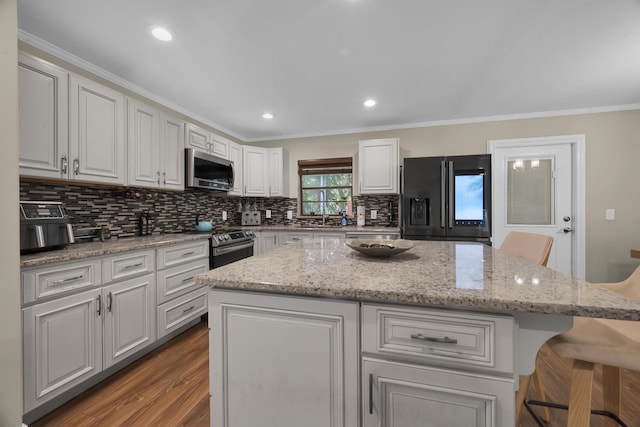 1966 9th St, Vero Beach, FL 32960 - kitchen with stainless steel appliances, a kitchen island, backsplash, a breakfast bar area, and white cabinetry