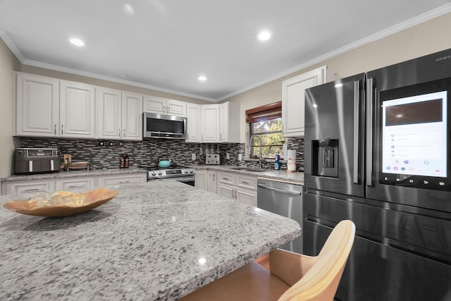 1966 9th St, Vero Beach, FL 32960 - kitchen featuring appliances with stainless steel finishes, tasteful backsplash, white cabinetry, light stone countertops, and ornamental molding