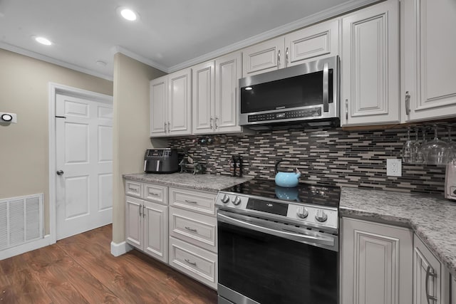 1966 9th St, Vero Beach, FL 32960 - kitchen with appliances with stainless steel finishes, crown molding, tasteful backsplash, dark wood-style flooring, and white cabinetry