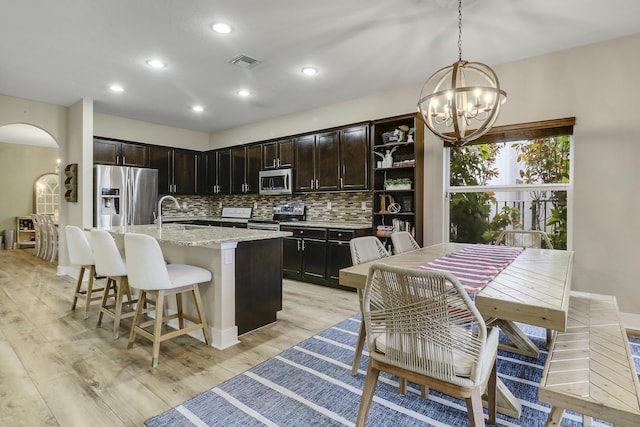 244 Behring Way, Jupiter, FL 33458 - kitchen with stainless steel appliances, arched walkways, backsplash, a chandelier, and light wood finished floors
