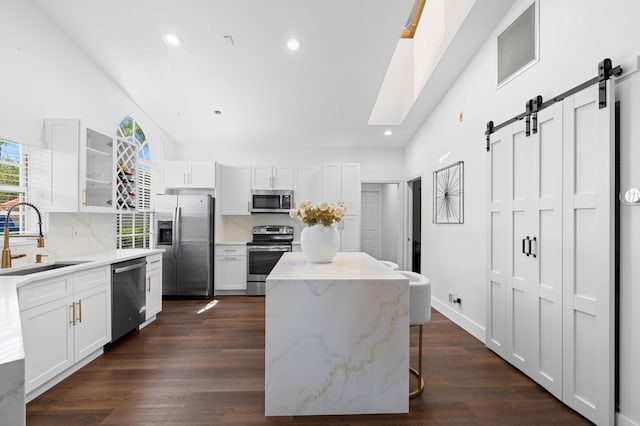 5160 Sabal Gardens Ln Unit 1, Boca Raton, FL 33487 - kitchen with appliances with stainless steel finishes, a barn door, backsplash, a kitchen island, and white cabinetry