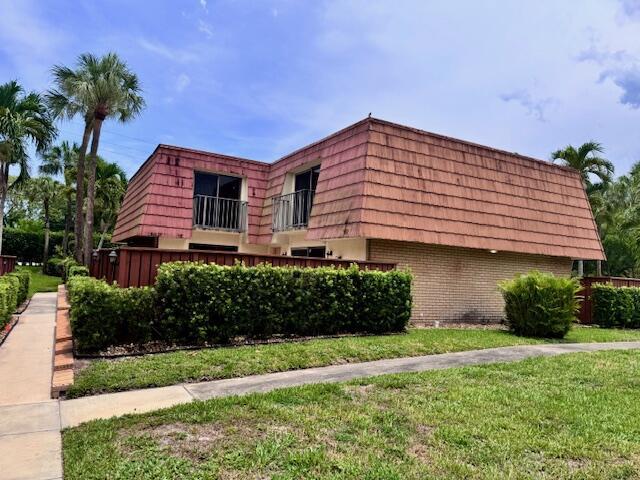 217 Live Oak Ln, Boynton Beach, FL 33436 - view of home's exterior featuring brick siding, mansard roof, a balcony, and a lawn