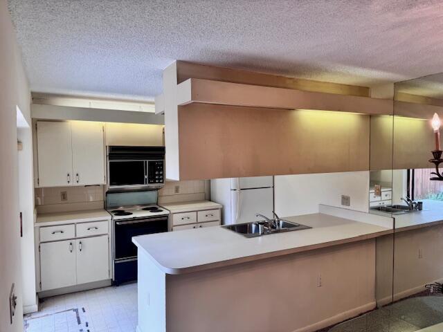 217 Live Oak Ln, Boynton Beach, FL 33436 - kitchen featuring white appliances, a peninsula, a textured ceiling, light countertops, and decorative backsplash