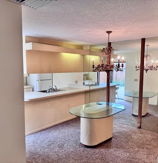 217 Live Oak Ln, Boynton Beach, FL 33436 - kitchen featuring a chandelier, freestanding refrigerator, carpet floors, a textured ceiling, and decorative light fixtures
