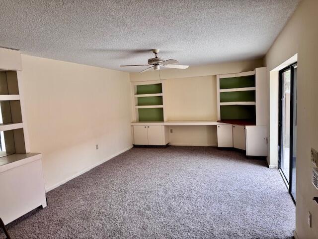 217 Live Oak Ln, Boynton Beach, FL 33436 - unfurnished living room with carpet, a textured ceiling, a ceiling fan, a desk, and built in features