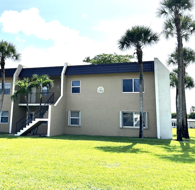 154 Lake Meryl Dr Unit 159, West Palm Beach, FL 33411 - back of house featuring stairs, stucco siding, and a yard
