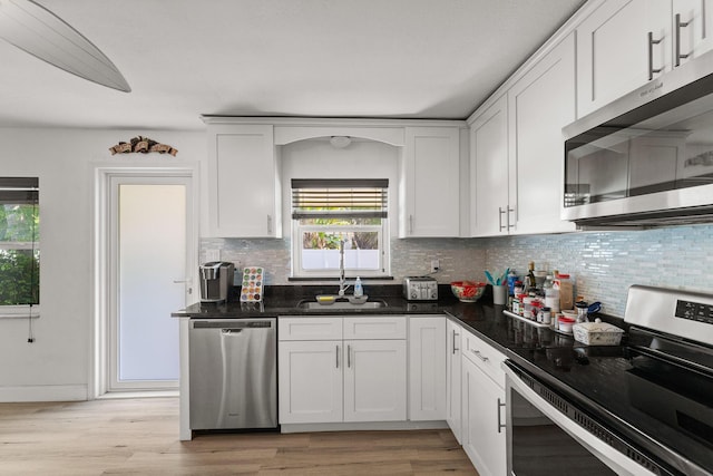 1144 NW 12th Ter, Stuart, FL 34994 - kitchen with stainless steel appliances, backsplash, white cabinetry, and light wood-style flooring