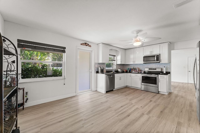 1144 NW 12th Ter, Stuart, FL 34994 - kitchen with stainless steel appliances, dark countertops, light wood finished floors, and tasteful backsplash