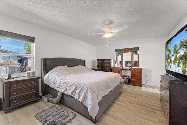 1144 NW 12th Ter, Stuart, FL 34994 - bedroom with light wood-style floors, a textured ceiling, and ceiling fan