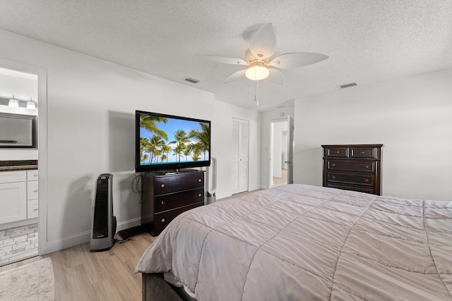 1144 NW 12th Ter, Stuart, FL 34994 - bedroom featuring light wood-type flooring, a textured ceiling, ensuite bathroom, and ceiling fan