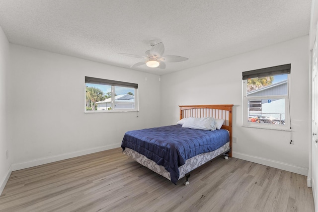 1144 NW 12th Ter, Stuart, FL 34994 - bedroom featuring multiple windows, wood finished floors, a textured ceiling, and a ceiling fan