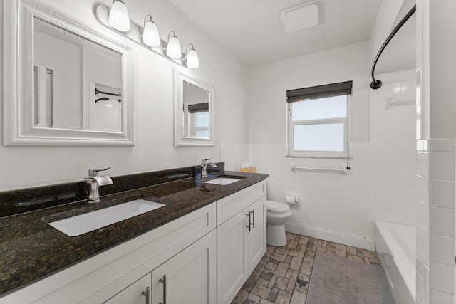 1144 NW 12th Ter, Stuart, FL 34994 - bathroom featuring tile walls, double vanity, wainscoting, and bathtub / shower combination